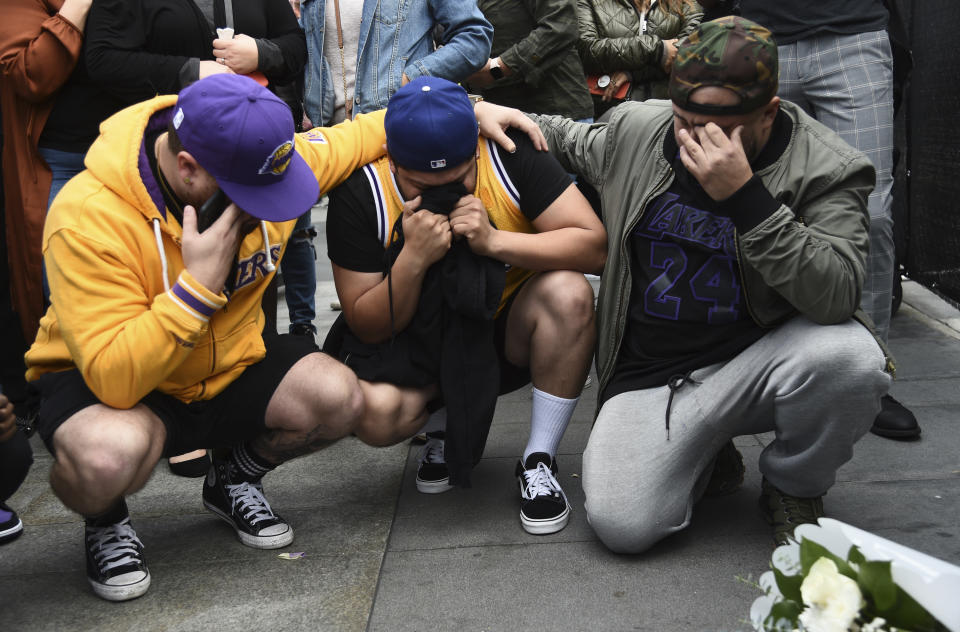 Los Angeles Laker fans Alex Fultz, from left, Eddy Rivas and Rene Alfaro mourn retired NBA star Kobe Bryant outside of the Staples Center prior to the 62nd annual Grammy Awards on Sunday, Jan. 26, 2020, in Los Angeles. Bryant died Sunday in a helicopter crash near Calabasas, Calif. He was 41. (AP Photo/Chris Pizzello)