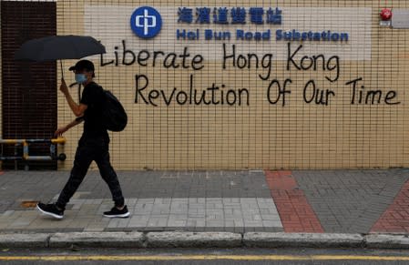 A demonstrator walks past a graffiti as he marches during a protest in Hong Kong