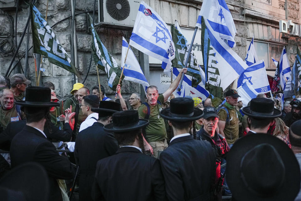 Members of the 'Brothers in Arms' reservist protest group wave Israeli flags during a demonstration in the ultra-Orthodox neighborhood of Mea Shearim, demanding equality in Israel's military service, in Jerusalem on Sunday, March 31, 2024. Ultra-Orthodox men have long received exemptions from military service, which is compulsory for most Jewish men, generating widespread resentment. The Supreme Court has ordered the government to present a new proposal for more equal service. (AP Photo/Ohad Zwigenberg)