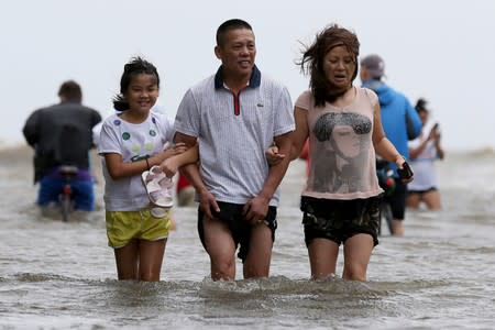 People wade through a flooded street after Hurricane Barry in Mandeville