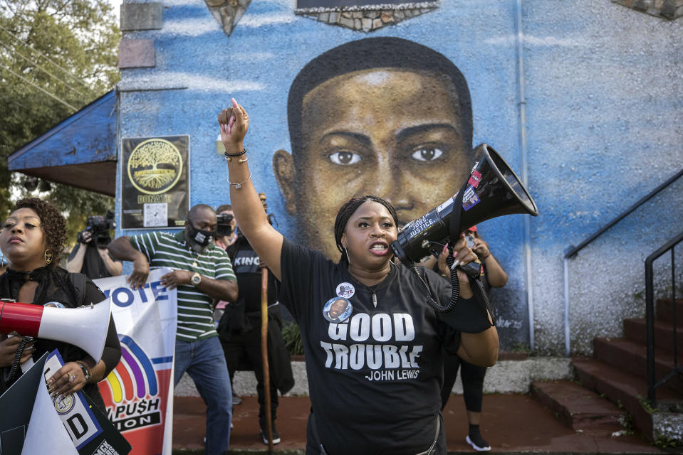 FILE - Civil rights activist Porchse Miller of Atlanta shouts into a megaphone in front of a mural of Ahmaud Arbery during march that followed the Wall of Prayer event outside the Glynn County Courthouse, Thursday, Nov. 18, 2021, in Brunswick, Ga. Three white men were later convicted of murder and federal hate crimes. (AP Photo/Stephen B. Morton, File)
