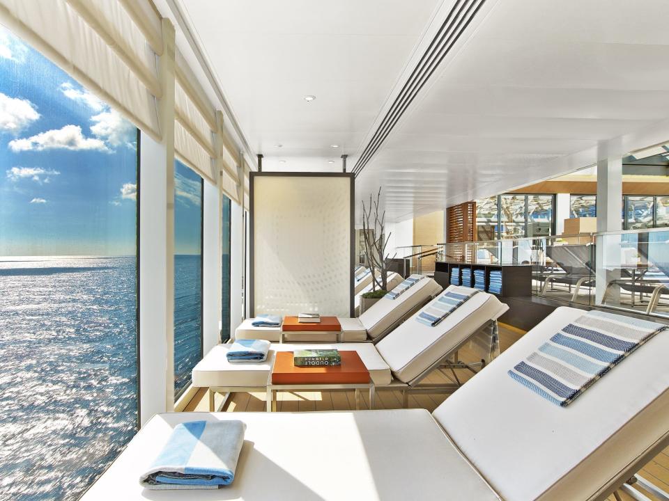 lounge chairs facing a glass wall with a view of the ocean