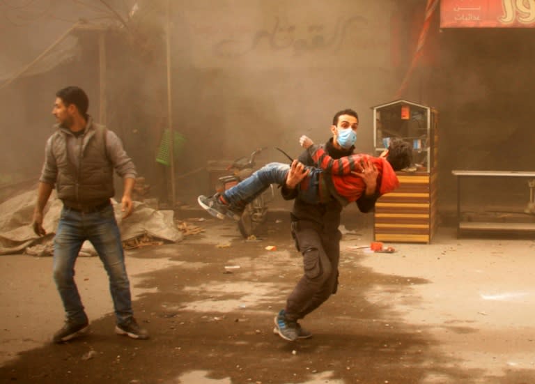 A Syrian Civil Defence member carries an injured child following regime air strikes on the rebel-held town of Douma on February 7, 2018