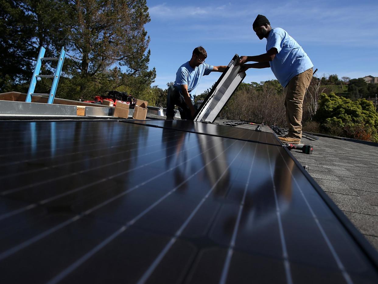 Workers install solar panels on the roof of a home in San Rafael, California: Getty
