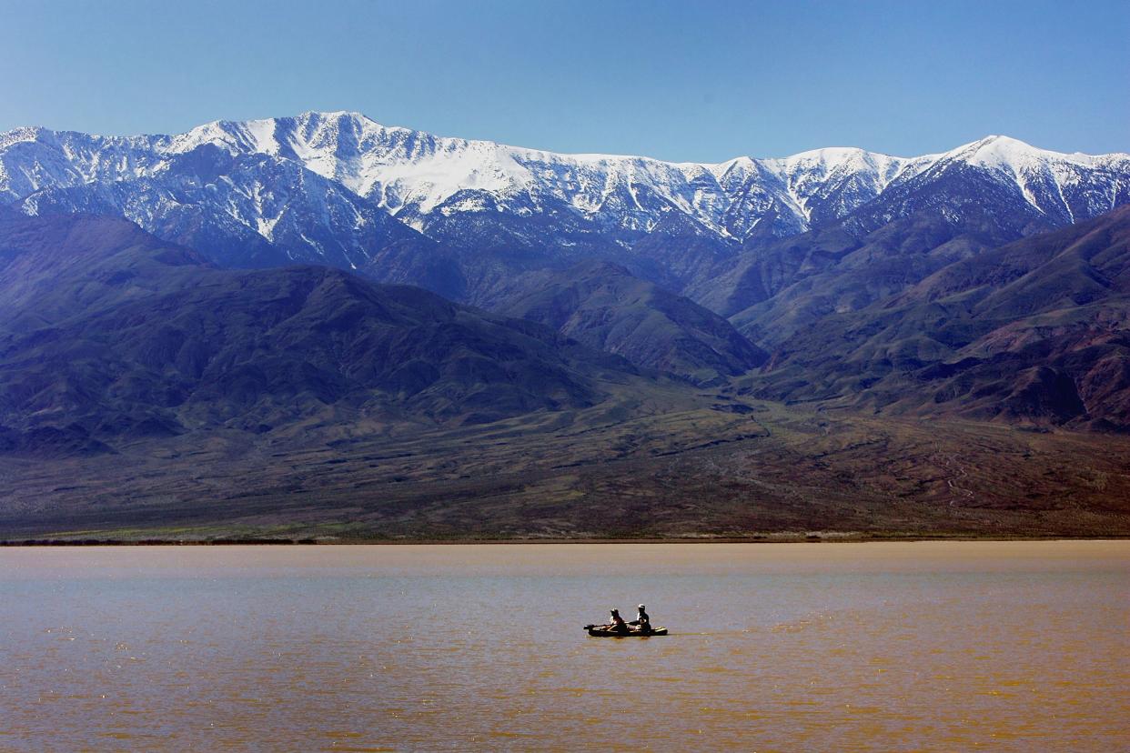 A couple kayaks on a giant lake in the bottom of Death Valley caused by heavy flooding in 2005. Pictured in the background are the snow-capped Panamint Mountains.