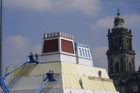 Operarios construyen una réplica del Templo Mayor azteca, con una imagen del dios precolombino Quetzalcoatl adornando los edificios colindantes, en la Plaza del Zócalo, en Ciudad de México, el 9 de agosto de 2021. La ciudad se está preparando para el 500 aniversario de la caída de la capital azteca, Tenochtitlan, hoy Ciudad de México, el 13 de agosto de 2021. (AP Foto/Eduardo Verdugo)