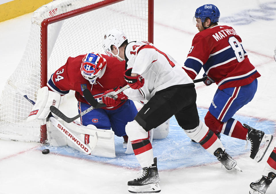 New Jersey Devils' Nathan Bastian (14) moves in on Montreal Canadiens goaltender Jake Allen as Canadiens' Mike Matheson (8) defends during the second period of an NHL hockey game Saturday, March 11, 2023, in Montreal. (Graham Hughes/The Canadian Press via AP)