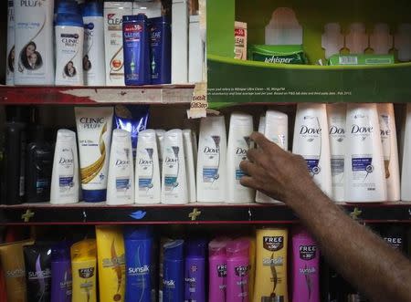 A salesman takes a bottle of Hindustan Unilever Limited (HUL) Dove shampoo from a shelf at a shop in Mumbai April 30, 2013. REUTERS/Danish Siddiqui/Files