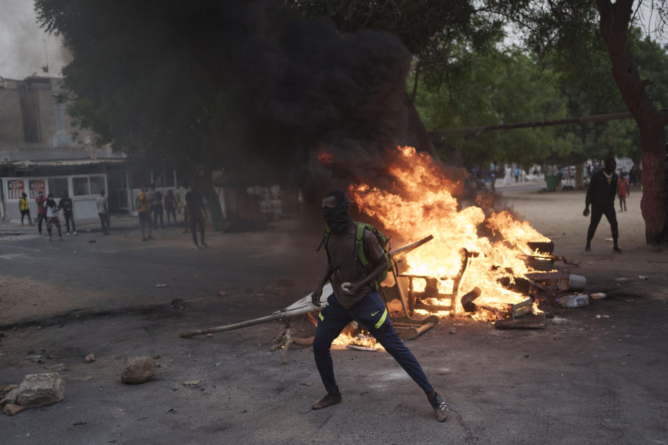 A demonstrator stands next to a barricade set on fire during a protest in support of the main opposition leader Ousmane Sonko in Dakar, Senegal, Monday, May 29, 2023. The clashes came a day after police stopped Sonko's "freedom caravan," traveling from his hometown of Ziguinchor, in the south and where he is the mayor, to the capital, Dakar, where he was forced into a home he has in the city. (AP Photo/Leo Correa)