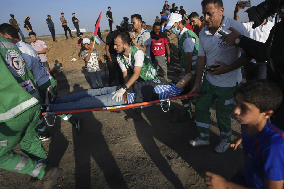 Medics evacuate a wounded journalist during clashes with Israeli troops, from the frontier with Israel, east of Gaza City, Monday, Aug. 21, 2023. Hundreds of Palestinians protested near the border fence with Israel. The Gaza Health Ministry said about eight people were wounded by Israeli fire and tear gas. (AP Photo/Adel Hana)
