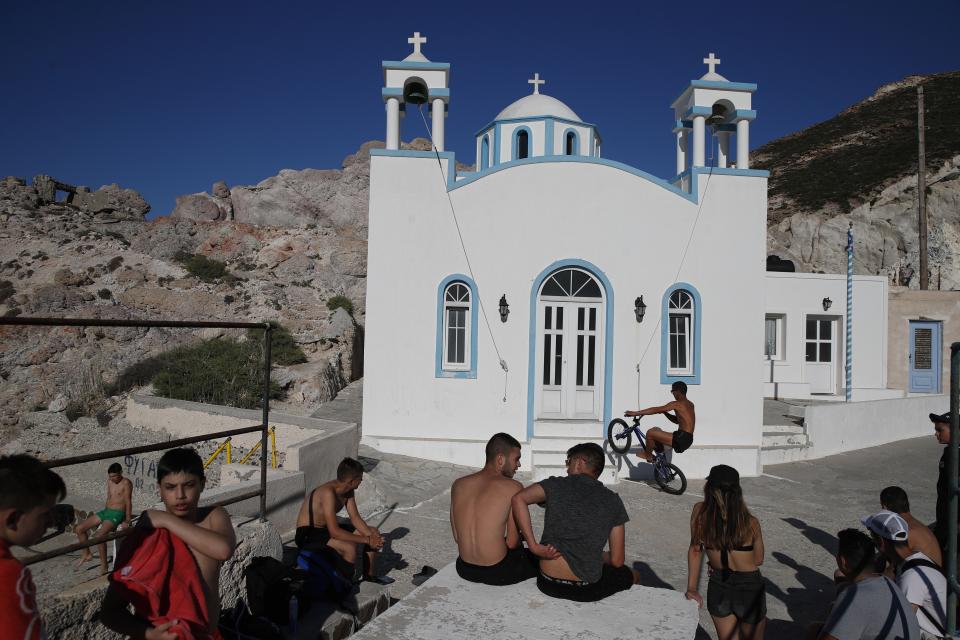 Children gather in front of a Greek Orthodox church on the Aegean Sea island of Milos, Greece, on Sunday, May 24, 2020. Greece's long-awaited tourist season will begin on June 15 with the opening of seasonal hotels and the arrival of the first foreign visitors, while international flights will begin heading directly for holiday destinations gradually as of July 1. (AP Photo/Thanassis Stavrakis)