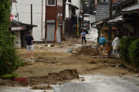 <p>Local residents stand outside their homes on a street filled with mud and silt following heavy flooding in Asakura, Fukuoka prefecture, on July 6, 2017. (Photo: Kazuhiro Nogi/AFP/Getty Images) </p>