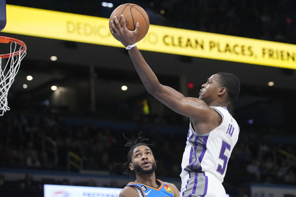 Sacramento Kings guard De'Aaron Fox (5) goes to the basket in front of Oklahoma City Thunder guard Isaiah Joe, left, in the first half of an NBA basketball game Sunday, Feb. 26, 2023, in Oklahoma City. (AP Photo/Sue Ogrocki)