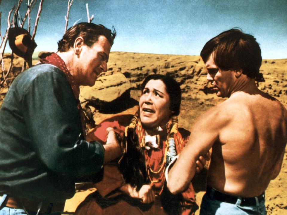 John Wayne as Ethan Edwards and a shirtless Jeffrey Hunter as Martin Pawley holding Beulah Archuletta as Wild Goose Flying in the Night Sky (Warner Bros)