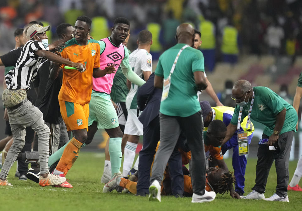 Ivory Coast's goalkeeper Ira Eliezer Tape, second from left, is surrounded by fans who invaded the playing field at the end of the African Cup of Nations 2022 group E soccer match between Ivory Coast and Algeria at the Japoma Stadium in Douala, Cameroon, Thursday, Jan. 20, 2022. (AP Photo/Themba Hadebe)