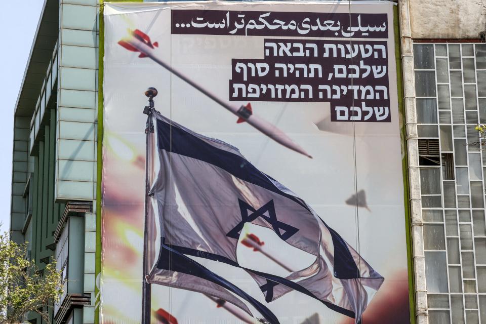 In Tehran, Iran, on April 14, 2024, a banner depicts missiles and drones flying past a torn Israeli flag. Israel's military said that with help from the United States and other allies, it shot down more than 300 missiles and drones launched by Iran as part of retaliation for an Israeli missile strike that killed Iranian military commanders earlier in the month in Syria.