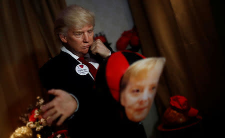 A performer with a mask of U.S. President Donald Trump slaps a punching ball with a mask of German Chancellor Angela Merkel in the Madame Tussauds wax museum in Berlin, Germany, August 14, 2018. REUTERS/Hannibal Hanschke