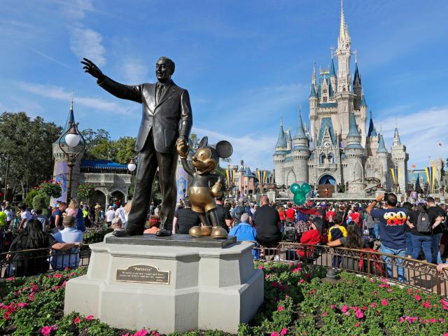 In this January 9, 2019, photo, guests watch a show near a statue of Walt Disney and Micky Mouse in front of the Cinderella Castle at the Magic Kingdom at Walt Disney World in Lake Buena Vista, Orlando, Florida.