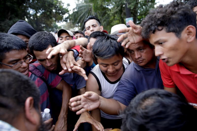 Migrants, mainly from Central America and marching in a caravan, gesture as they wait to receive food near Frontera Hidalgo, Chiapas