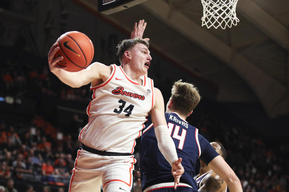 Oregon State forward Tyler Bilodeau (34) passes the ball behind Arizona center Motiejus Krivas (14) beneath the basket during the first half of an NCAA college basketball game Thursday, Jan. 25, 2024, in Corvallis, Ore. (AP Photo/Amanda Loman)