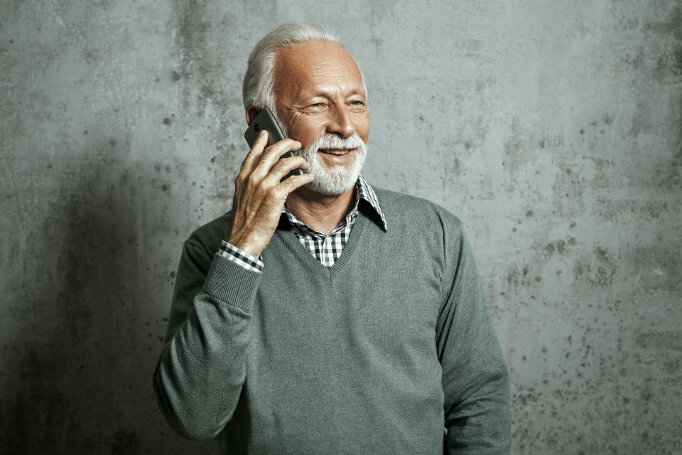 Senior man in sweater holding smart phone