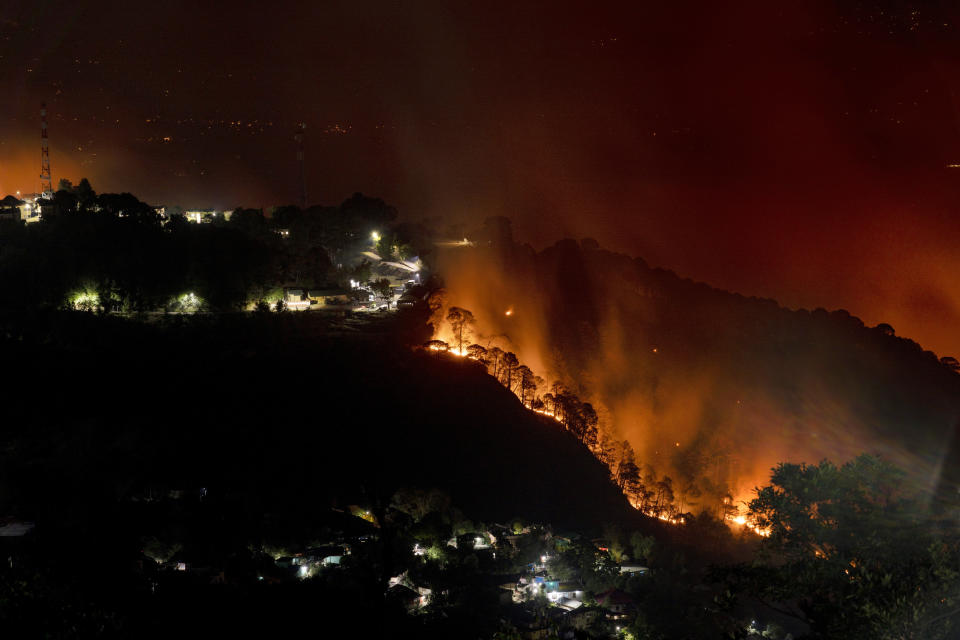 A forest on a mountain slope next to a township is seen on fire in Dharmsala, India, Monday, April, 25, 2022. The intense heat wave sweeping through South Asia was made more likely due to climate change and is a sign of things to come. An analysis by international scientists said that this heat wave was made 30 times more likely because of climate change and future warming would make heat waves more common and hotter in the future. Its effects have been cascading, ranging from forest fires and glacial floods to crop losses that forced India to ban exports on wheat. (AP Photo/Ashwini Bhatia, file)