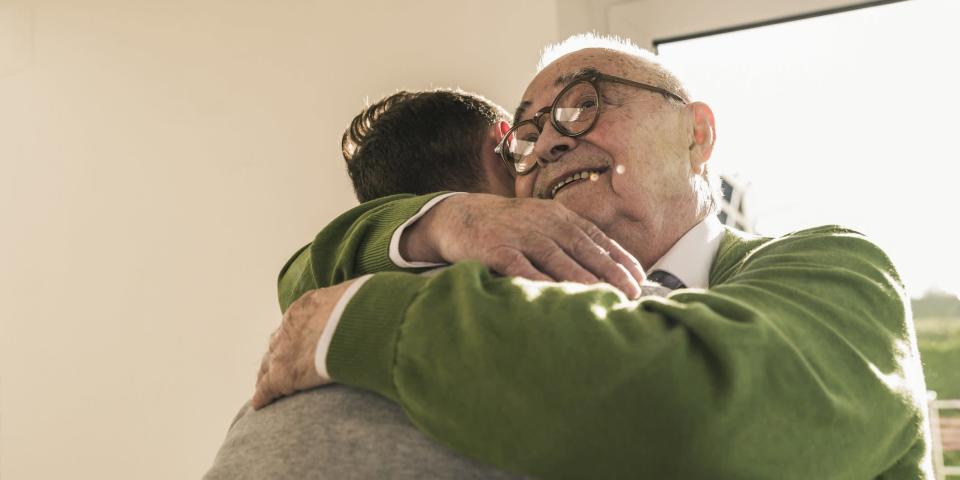 Smiling senior man hugging young man
