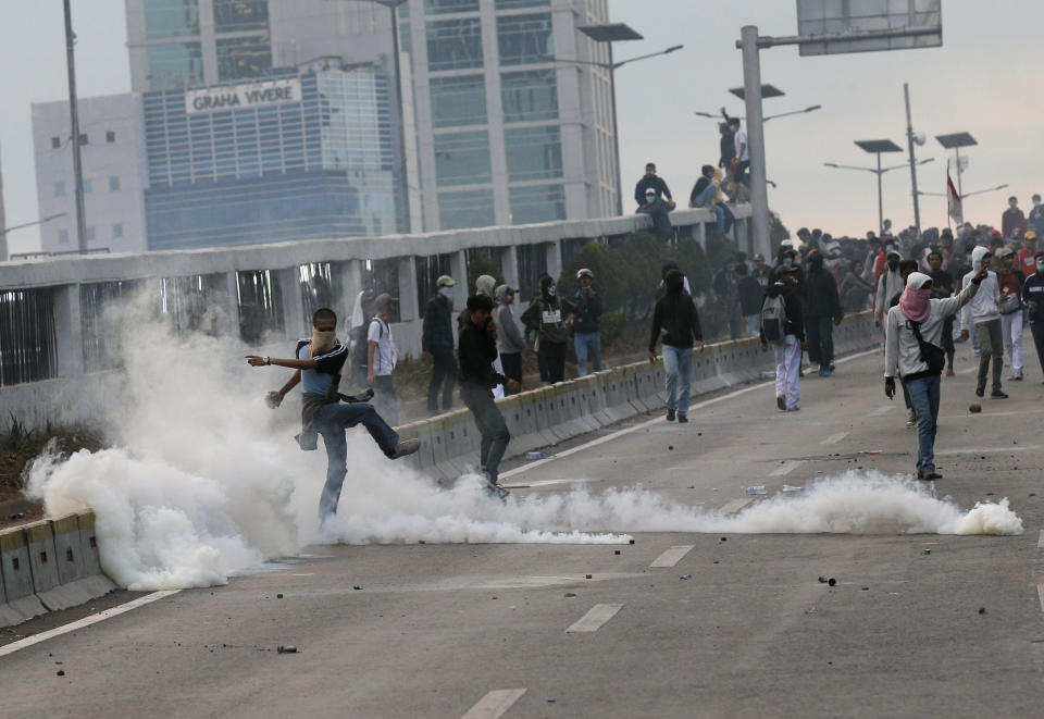 A student protester kicks a tear gas canister during a clash in Jakarta, Indonesia, Monday, Sept. 30, 2019. Thousands of Indonesian students resumed protests on Monday against a new law they say has crippled the country's anti-corruption agency, with some clashing with police. (AP Photo/Tatan Syuflana)