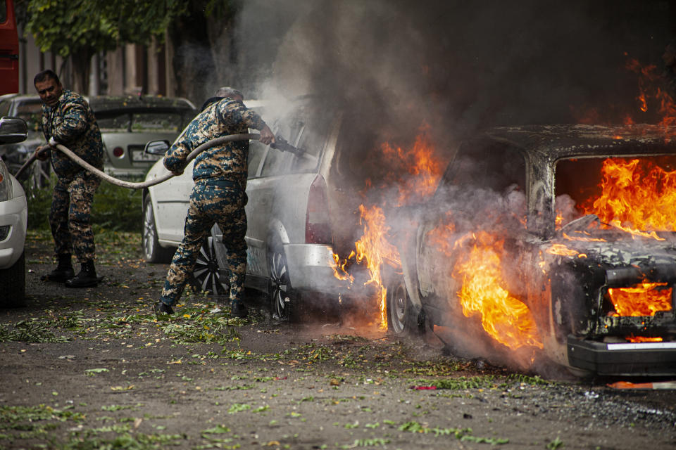 Firefighters work on a car burning, after shelling by Azerbaijan's artillery in Stepanakert, the self-proclaimed Republic of Nagorno-Karabakh, Azerbaijan, Sunday, Oct. 4, 2020. Heavy fighting between Azerbaijani and Armenian forces in the region since Sept. 27 has killed scores of both servicemen and civilians. Nagorno-Karabakh lies inside Azerbaijan but has been under the control of ethnic Armenian forces backed by Armenia since the 1994. (AP Photo/Karen Mirzoyan)