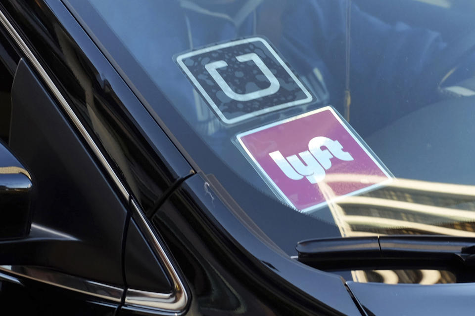 FILE - In this Jan. 12, 2016, file photo, a ride share car displays Lyft and Uber stickers on its front windshield in downtown Los Angeles. The future of Uber and Lyft in Minneapolis has been a source of concern and debate in recent weeks after the City Council voted last month to require that ride-hailing companies pay drivers a higher rate while they are within city limits. (AP Photo/Richard Vogel, File)