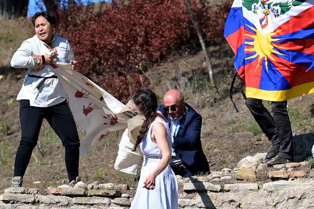 A security officer tries to stop protesters holding a banner and a Tibetan flag as they crash the flame lighting ceremony for the Beijing 2022 Winter Olympics.  (Photo: ARIS MESSINIS via Getty Images)