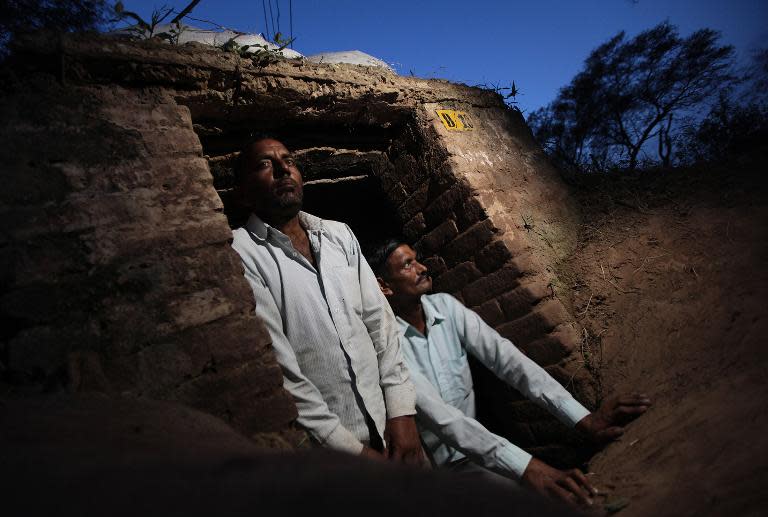 Indian villagers gather near the bodies of those killed in cross-border firing between Indian and Pakistani troops at Jeiora village in the RS Pura sector near Jammu on August 23, 2014