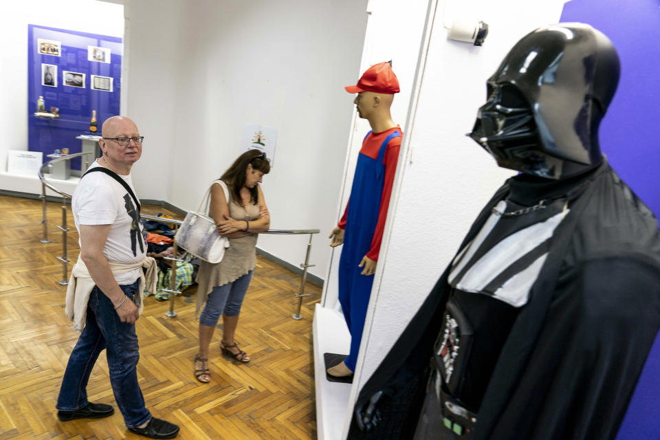 In this photo taken on Friday, July 12, 2019, visitors walk past a mannequin of Darth Vader, on display in an exhibition at the National History Museum, in Kiev, Ukraine. A Darth Vader costume, playground equipment, pastries and boxes of food all are part of an exhibit at Ukraine’s National History Museum displaying the colorful behavior and sometime-questionable practices that characterize the country’s elections. The exhibition, called “The Museum of Election Trash” was put together ahead of the snap parliamentary elections on Sunday, July 21, 2019. (AP Photo/Evgeniy Maloletka)