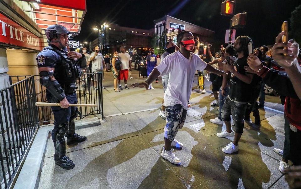 Protesters surround Louisville Metro Police Department officer Galen Hinshaw in front of Bearno's restaurant on Thursday, May 28, 2020 in Louisville, Kentucky.  Five strangers linked arms to keep the crowd from getting to Hinshaw.