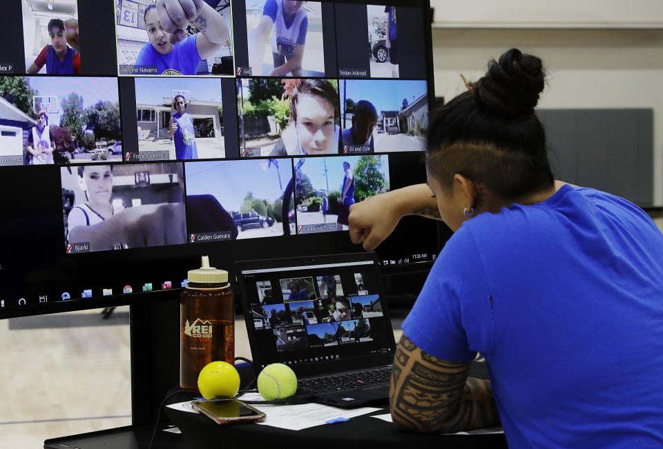 In this photo taken on Tuesday, June 9, 2020, VeAnne Navarro has a virtual fist bump with students including Bjarki Robertsson, lower left on screen, of Reykjavik, Iceland at Golden State Warriors basketball camp in Oakland, Calif. The Warriors had to adapt their popular youth basketball camps and make them virtual given the COVID-19 pandemic. (AP Photo/Ben Margot)