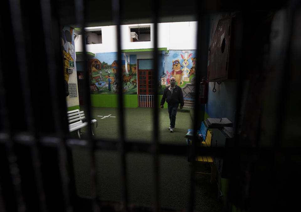 School employee Joel Barbas walk inside the empty Benito Juarez school amid the new coronavirus pandemic, as students return to classes but not schools in Mexico City, Monday, Aug. 24, 2020. A system cobbling together online classes, instruction broadcast on cable television channels and radio programming in indigenous languages for the most remote, will attempt to keep students from missing out. (AP Photo/Marco Ugarte)