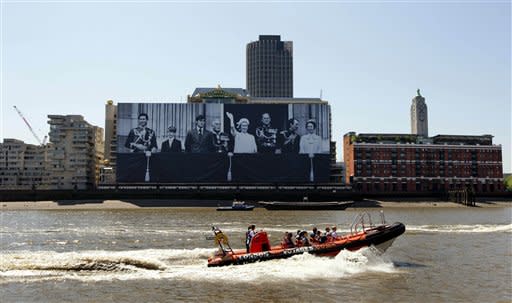 A boat passes a giant image hanging from a building on the south bank of the River Thames in London showing Britain's Queen Elizabeth II, fifth left, and from left the royal family, Prince Charles, Prince Edward, Prince Andrew, Earl Mountbatten, Prince Phillip, Mark Phillips and Princess Anne standing on the balcony of Buckingham Palace during the Queen's 1977 Silver Jubilee, Friday, May 25, 2012. The giant canvas, measuring 100 meters by 70 meters and weighing nearly two tons, was officially unveiled on Friday and will be displayed until the end of June, in celebration of the Diamond Jubilee, marking the Queen's 60 year reign. (AP Photo/Matt Dunham)