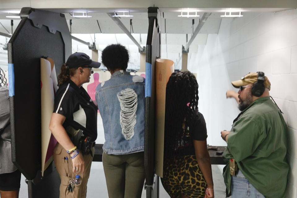 In this Aug. 21, 2021, image taken from video, firearms instructors, left, and right, teach female customers on the shooting range at the Recoil Firearms store in Taylor, Mich. About 1,000 or so mostly Black women took part in free weekend gun safety and shooting lessons at two Detroit-area ranges. Black women increasingly are considering gun ownership for personal protection, according to industry experts and gun rights advocates. (AP Photo/Carlos Osorio)