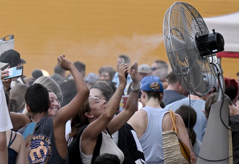 Turistas buscan refrescarse antes de entrar al Coliseo romano. (Tiziana FABI / AFP)