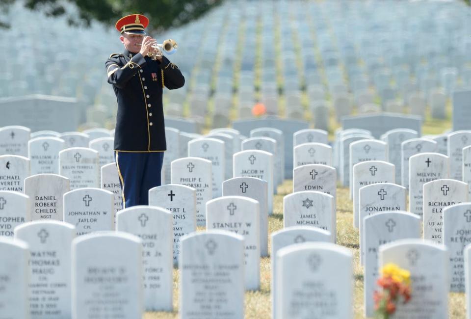 In this file photo from 2013, a bugler plays Taps during the burial service at Arlington National Cemetery in Arlington, Virginia, for Army Air Force 2nd Lt. Valorie L. Pollard and Army Air Force Sgt. Dominick J. Licari, who went missing during World War II. Such traditional military funeral ceremonies are largely on hold due to the coronavirus pandemic. Veterans affairs officials say that as soon as it is safe, the playing of taps and rifle salutes will be done for those veterans who have passed away during this time of social distancing.