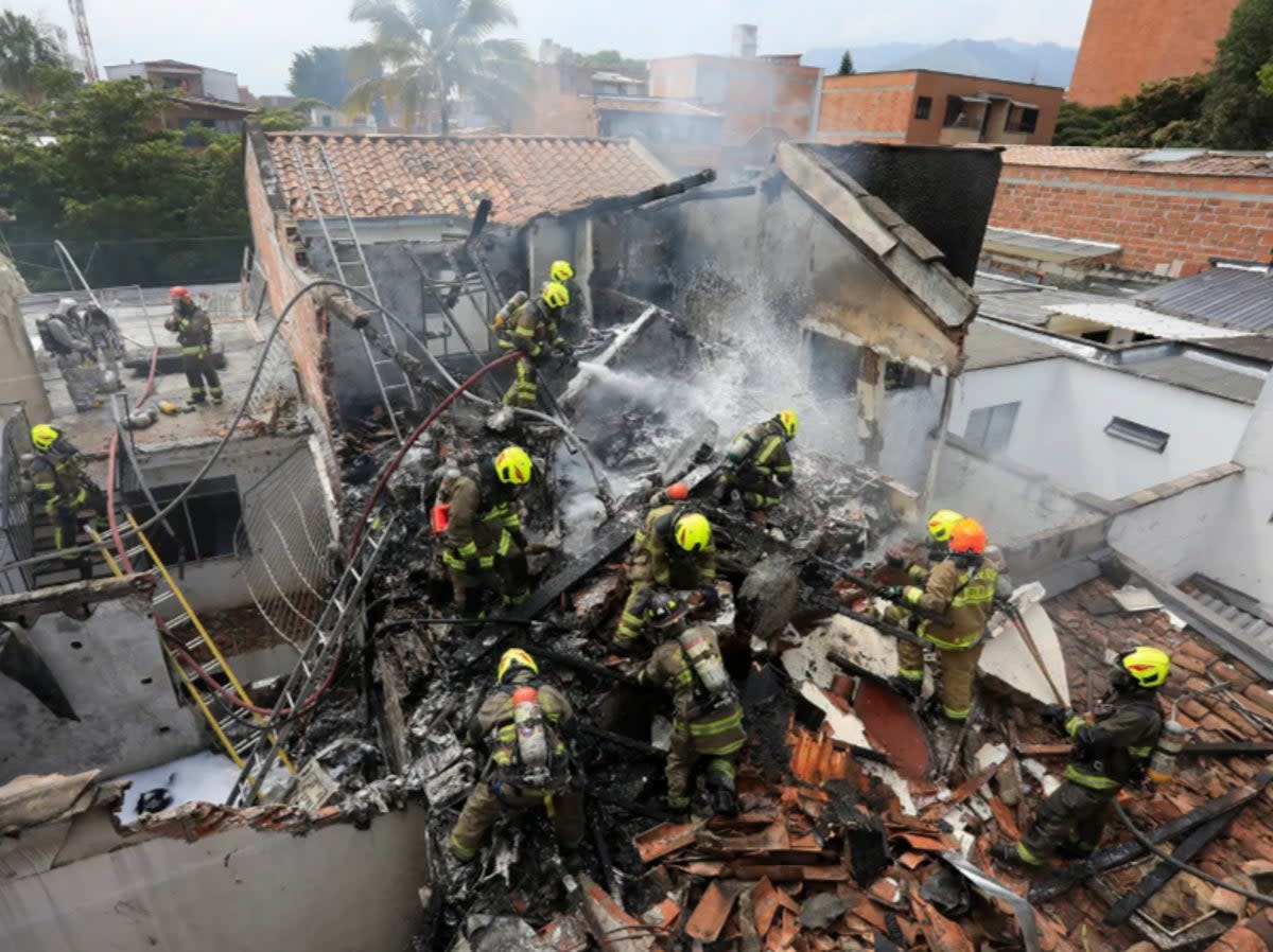 Firefighters at the scene of the crash in Medellin, Colombia where an aircraft carrying eight people crashed and killed all on board (AP)