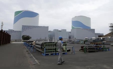 An employee of Kyushu Electric Power Co walks in front of reactor buildings at the company's Sendai nuclear power plant in Satsumasendai, Kagoshima prefecture April 3, 2014. REUTERS/Mari Saito