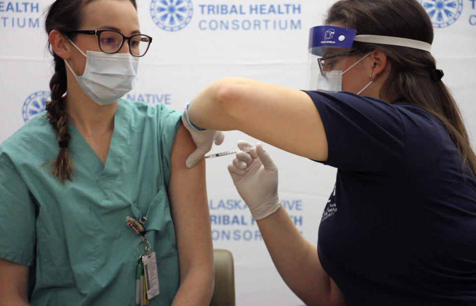 FILE - In this Tuesday, Dec. 15, 2020, file photo, Rachel Kelly, left, an intensive care unit nurse, receives a dose of COVID-19 vaccine from Emily Schubert, the employee health nurse at the Alaska Native Medical Center in Anchorage, Alaska. Alaska has dropped restrictions on who can get a COVID-19 vaccination, opening eligibility to anyone 16 or older who lives or works in the state in a move that Gov. Mike Dunleavy said could help Alaska's pandemic-battered economy. The Republican, who highlighted his own bout with COVID-19 in making the announcement Tuesday, March 9, 2021, said Alaska is the first U.S. state to remove eligibility requirements. (AP Photo/Mark Thiessen)