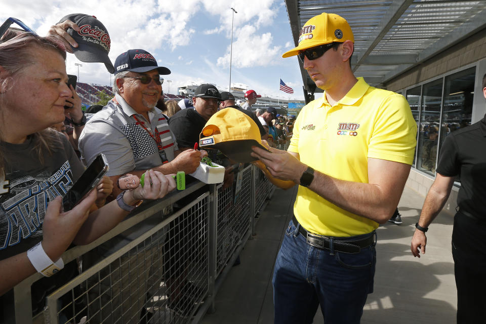 Driver Kyle Busch, right, gives autographs to fans prior to a NASCAR Cup Series auto race at ISM Raceway, Sunday, Nov. 10, 2019, in Avondale, Ariz. (AP Photo/Ralph Freso)