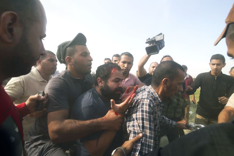 Palestinos llevan a un civil israelí capturado, en el centro, desde el kibbutz Kfar Azza a la Franja de Gaza