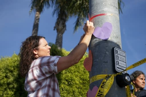 A woman puts up a note across the street from the Chabad of Poway Synagogue