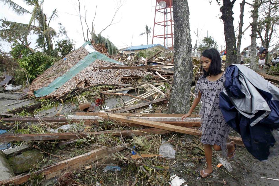 A resident walks past her collapsed house after super Typhoon Haiyan battered Tacloban city, central Philippines, November 9, 2013. Possibly the strongest typhoon ever to hit land devastated the central Philippine city of Tacloban, killing at least 100 people, turning houses into rubble and leveling the airport in a surge of flood water and high wind, officials said on Saturday. The toll of death and damage from Typhoon Haiyan on Friday is expected to rise sharply as rescue workers and soldiers reach areas cut off by the massive, fast-moving storm which weakened to a category 4 on Saturday. REUTERS/Romeo Ranoco (PHILIPPINES - Tags: DISASTER ENVIRONMENT)