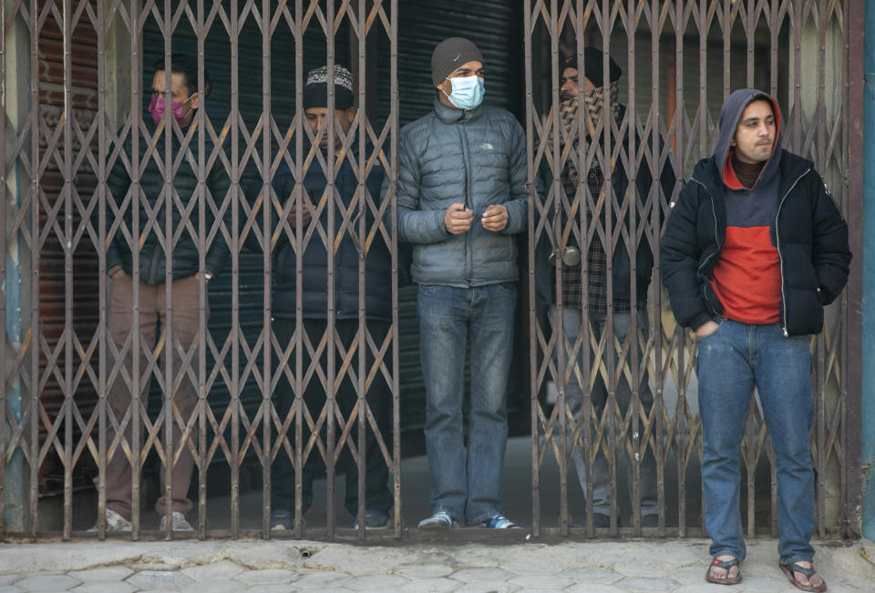 Nepalese shopkeepers stand in front of their closed shop during a general strike in Kathmandu, Nepal, Thursday, Feb. 4, 2021. A general strike called by a splinter faction of the ruling Communist party paralyzed life in Nepal on Thursday, shutting down schools, transportation and markets. Highways were deserted and shops were closed by the strike protesting Prime Minister Khadga Prasad Oli's decision to dissolve Parliament and call new elections. (AP Photo/Niranjan Shrestha)