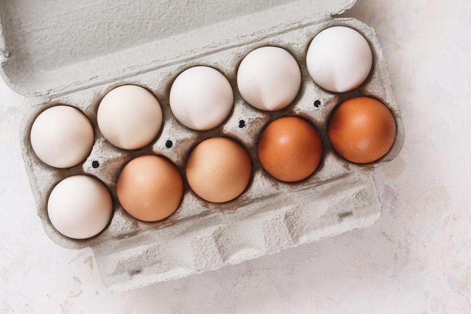 a photo of different color eggs in a carton