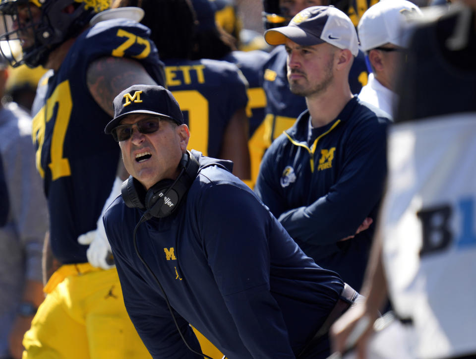 BESTAND - Hoofdcoach Jim Harbaugh uit Michigan, linksvoor, kijkt toe tegen Rutgers als assistent Connor Stallions, rechts, kijkt toe tijdens een NCAA universiteitsvoetbalwedstrijd in Ann Arbor, Michigan, 23 september 2023. Een rechter uit Michigan die pleit voor vredeshandhavingsprincipes in de rechtbank zal vrijdag een hoorzitting voorzitten die zal bepalen of Jim Harbaugh het reguliere seizoen op het veld kan coachen en afsluiten met de op de derde plaats geplaatste Wolverines. Advocaten van Harbaugh en de universiteit vragen rechter Timothy P. Connors om op zijn minst tijdelijk de straf van de Big Ten tegen hem op te heffen wegens het stelen van borden. (AP Foto/Paul Sancya, BESTAND)